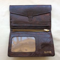 Vintage brown  leather bi-fold wallet, 1970s W 4 inches  10 cm H 6.5 inches  16.5 cm Inside left, tab and strap that give access to complete width and length of wallet back compartment. Three slip in pockets. Central metal zip gives access to another complete width and length of wallet back compartment. Right side has one slip in pocket for notes,  plus card pocket and stamps pocket, plus one vinyl window pocket.Rich dark brown textured leather with foil markings, made in China, real leather. Ve Vintage Brown Bifold Wallet For Daily Use, Vintage Brown Wallets With Leather Lining, Vintage Brown Wallet With Leather Lining, Vintage Leather Trifold Wallet With Coin Pocket, Vintage Brown Trifold Wallet With Coin Pocket, Vintage Wallets With Snap Closure For Everyday Use, Vintage Trifold Wallet With Coin Pocket For Travel, Vintage Wallets With Snap Closure, Vintage Leather Trifold Wallet For Travel