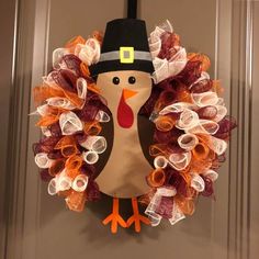 a wreath with a turkey wearing a pilgrim's hat on it is hanging on the front door