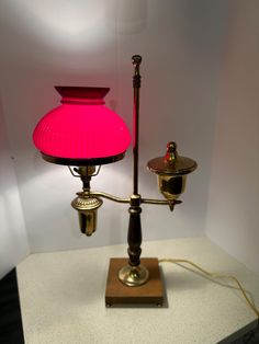 a pink lamp sitting on top of a table next to a light fixture with a red shade