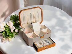 an open jewelry box sitting on top of a table next to a vase with flowers