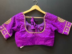 Purple Color Soft Silk Readymade Blouse with beautiful Handwork Work. Golden Color Beads and Sequence Work with beautiful tassels. Item : Readymade BlouseSize : 36 (Can be opened to Size 40)Length of the Blouse : 14 inches Length of the Sleeves : 10 inches Color : Purple Blouse Fabric : Soft Silk Lining : Yes, it is fully lined Padded or Non-Padded : PaddedClosure: Front Closure with hooks.Ready-to-Wear : YesDisclaimer - : -This is a Standard Size blouse. We do not guarantee perfect fit as every Traditional Blouse With Tassels For Festive Occasions, Traditional Festive Blouse With Tassels, Festive Traditional Blouse With Tassels, Bollywood Style Blouse Piece With Tassels, Elegant Purple Blouse For Navratri Festival, Elegant Purple Navratri Blouse, Traditional Embellished Purple Blouse Piece, Blouse Handwork, Padded Blouse