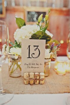 the table numbers are displayed in mason jars with candles and flowers behind them, along with wine corks