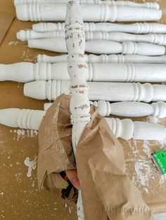 several white candles are being made out of paper and wrapped in brown paper with green tags on them