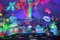 an indoor tent decorated with bright lights and decorations for a party or event, including paper flowers