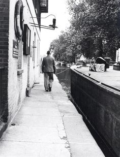 a man walking down a sidewalk next to a river