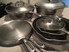 several pots and pans are sitting on the counter top with utensils next to them