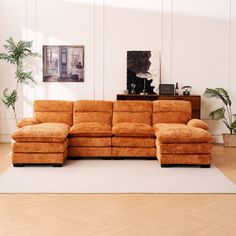 a large sectional couch sitting on top of a wooden floor next to a white rug