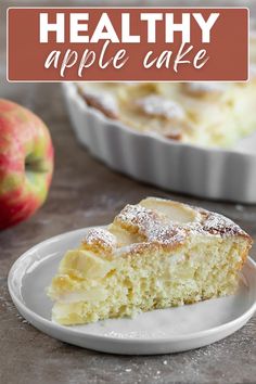 a close up of a slice of cake on a plate with an apple in the background