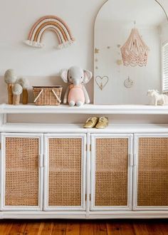 a white dresser with wicker doors and baskets on top in a child's room