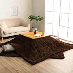 a living room with a couch, coffee table and potted plant on the floor