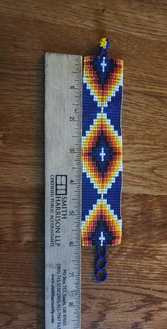 a ruler is sitting next to a beaded keychain on a wooden surface