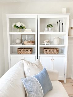 a white couch sitting in front of a book shelf filled with books and vases