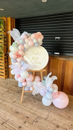 a balloon arch with flowers and leaves on it for a baby's first birthday