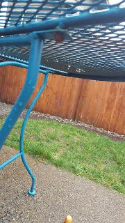 an orange sitting on the ground next to a blue metal table with a hole in it