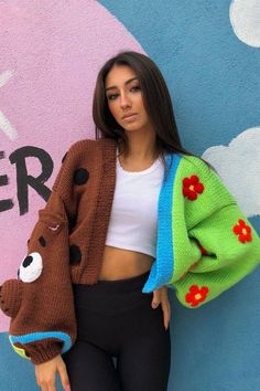 a woman standing in front of a wall with a teddy bear sweater over her shoulders