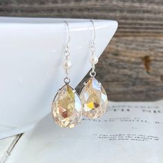 These earrings feature stunning Vintage glass crystal jewels in an antiques silver setting. They are an amazing light golden champagne color with loads of sparkle. They are dangled below Swarovski Crystal pearls wrapped onto sterling silver wire. Hung on sterling silver French hook earwires. These earrings are 42mm king or just over 1 and 5/8 inches including earwires. Jewels are 21mm tall and 13mm wide. * These earrings feature Vintage findings. They are very limited to stock on hand. Jewel Earrings, Golden Champagne, Jeweled Earrings, Holiday Earring, Champagne Color, Silver Rhinestone, Support Handmade, Earrings Vintage, Glass Crystal