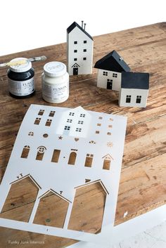 cut out paper houses sitting on top of a wooden table next to paint and glue