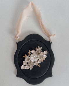 a black and white brooch with flowers on it's side hanging from a ribbon