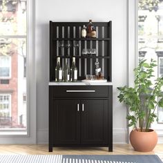 a black cabinet with wine glasses and bottles on it next to a potted plant