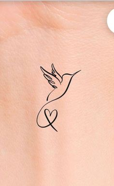 a small tattoo on the back of a woman's shoulder with a bird flying over it