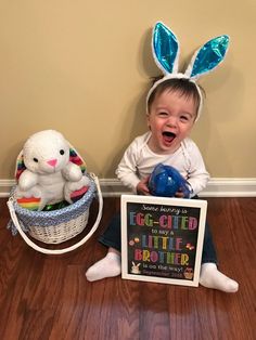 a baby sitting on the floor with an easter sign