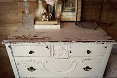 an old white dresser with some flowers on top