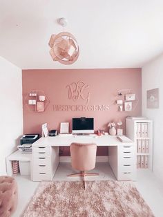 a white desk topped with a laptop computer next to a pink chair and wall art