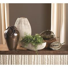 three vases sitting on top of a table next to each other with plants in them