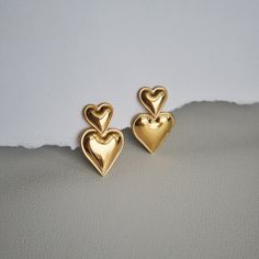 The Double Heart Drop Earrings will add a touch of love to any outfit. With their playful dangle design and bold heart shape, they're the perfect statement earrings for a girls night out or date night. Perfect for anyone who wants to show off their fun-loving side and spread lots of love wherever they go! - stainless steel, gold plated Trendy Earrings For Anniversary And Mother's Day, Heart Shaped Metal Earrings For Valentine's Day, Heart-shaped Metal Earrings For Valentine's Day, Trendy Heart Charm Earrings For Anniversary, Trendy Heart Charm Earrings For Mother's Day, Trendy Heart Drop Earrings For Anniversary, Trendy Heart-shaped Drop Earrings For Anniversary, Trendy Heart-shaped Earrings For Mother's Day, Trendy Anniversary Heart Drop Earrings