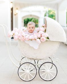 a baby in a white carriage with pink flowers