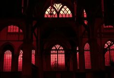 the inside of a building with many windows and arches on it's sides, all lit up by red light