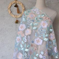 a mannequin wearing a dress with flowers on it next to a necklace and ring