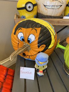 several pumpkins with faces painted on them sitting on a shelf next to other decorations