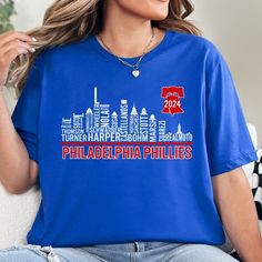 Philadelphia Phillies Skyline Shirt featuring the names of many of this years popular players including all opening day starters and all-star players. *Not every Phillies Player is listed due to continuous changes in roster so please refer to the product photos to see which players are featured* ~Bella & Canvas Brand Shirt ~99% ring-spun cotton, 1% polyester ~All shirts are unisex adult sizing ~ all props in photos are not included with purchase and rolled sleeves in photos are for styling purposes only  Printing ~ All designs are printed using Print-to-Garment ink, not vinyl, so there will not be any peeling or cracking ~ Ink is infused into the fabric, not sitting on top of the fabric ~ Shirts are made to order so there may be slight variations in design colors ~ Designs change slightly Short Sleeve Tops For Baseball Season Fan Events, Team Name Tops For Baseball Season Fan Events, Baseball Season Tops With Team Name For Fan Events, Baseball Season Tops With Letter Print For Fan Events, Letter Print Tops For Baseball Season Fan Events, Brandon Marsh, Skyline Shirt, Alec Bohm, Phillies Shirt