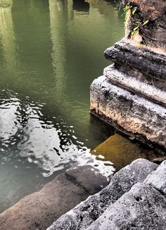 the water is green and clear in this area with stone steps leading up to it