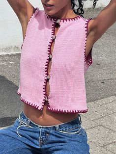 a woman in jeans and a pink top is holding her hair up to her head