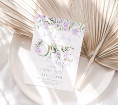 a white plate topped with a card next to an open palm tree leaf and a fan