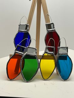 four different colored glass vases sitting on top of a white table next to a wooden easel