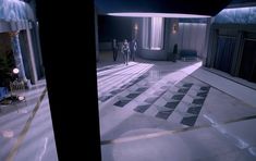 two people are standing in the middle of a large room with marble floors and walls