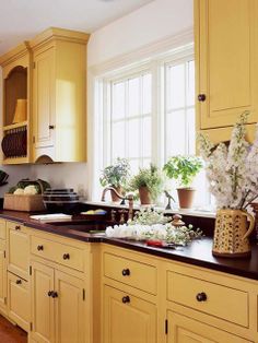 a kitchen filled with lots of yellow cupboards and counter top next to a window