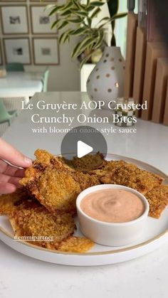 a plate with some food on it and a person dipping sauce in the bowl next to it