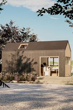 a small house sitting on top of a gravel road next to trees and bushes in front of it