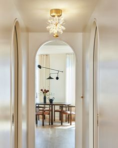 an arched doorway leads to a dining room and living room with a table in the center