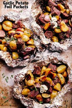 three foil packets filled with potatoes and meat