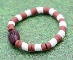 Youth Boy's American Football Themed Polymer Clay Trending Sports Themed Stretch Bracelet - Brown and White(Boring title. We know. We are trying to appease the algorithm deity). Football! Football! Football! This brown and white bracelets is inspired by the old pig skin (not literally, we are using a slang for the word football) hitting the field. Hut Hut Hike! Material Used:Green and Brown Polymer Clay Beads(1) Plastic Brown Football BeadNylon Stretch String Bracelets come in sizes: 5 inches an Cheap Casual Sports Beaded Bracelets, Football Hits, Browns Football, Jackson Mississippi, String Bracelets, Football Football, White Bracelets, Little Monkeys, String Bracelet