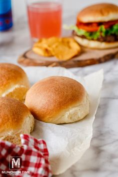 two buns sitting on top of a table next to a glass of water and some chips