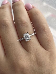 a woman's hand with a diamond ring on top of her finger and the engagement band