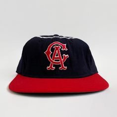 "Here is a rare display item from the \"Golden Age of Baseball\". Offered is an original California Angels KM Pro cap from the 1960s. The cap features the California Angels interlocking \"CA\" logo on the front, red bill and silver halo stitched around the crown. The six-point crown suspension's interior is lined with a leather sweatband that is home to a vintage \"KM Pro\" label. This cap is labeled as a size \"7\". Features - Color: navy, silver and red - Interlocking \"CA\" logo on the front Vintage Baseball Cap For Baseball Season, Retro Six-panel Baseball Cap For Baseball Season, Vintage Six-panel Baseball Cap For Baseball Season, Retro Six-panel Baseball Hat, Retro Six-panel Hat For Baseball Season, Retro Six-panel Fitted Hat For Baseball Season, Vintage Six-panel Trucker Hat For Baseball Season, Vintage Baseball Cap With Curved Brim, Vintage Red Six-panel Baseball Cap