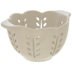 a white bowl with holes in the middle and leaves on it's sides,