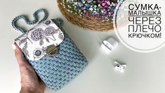 a hand holding a blue purse next to an earbud holder with beads on it